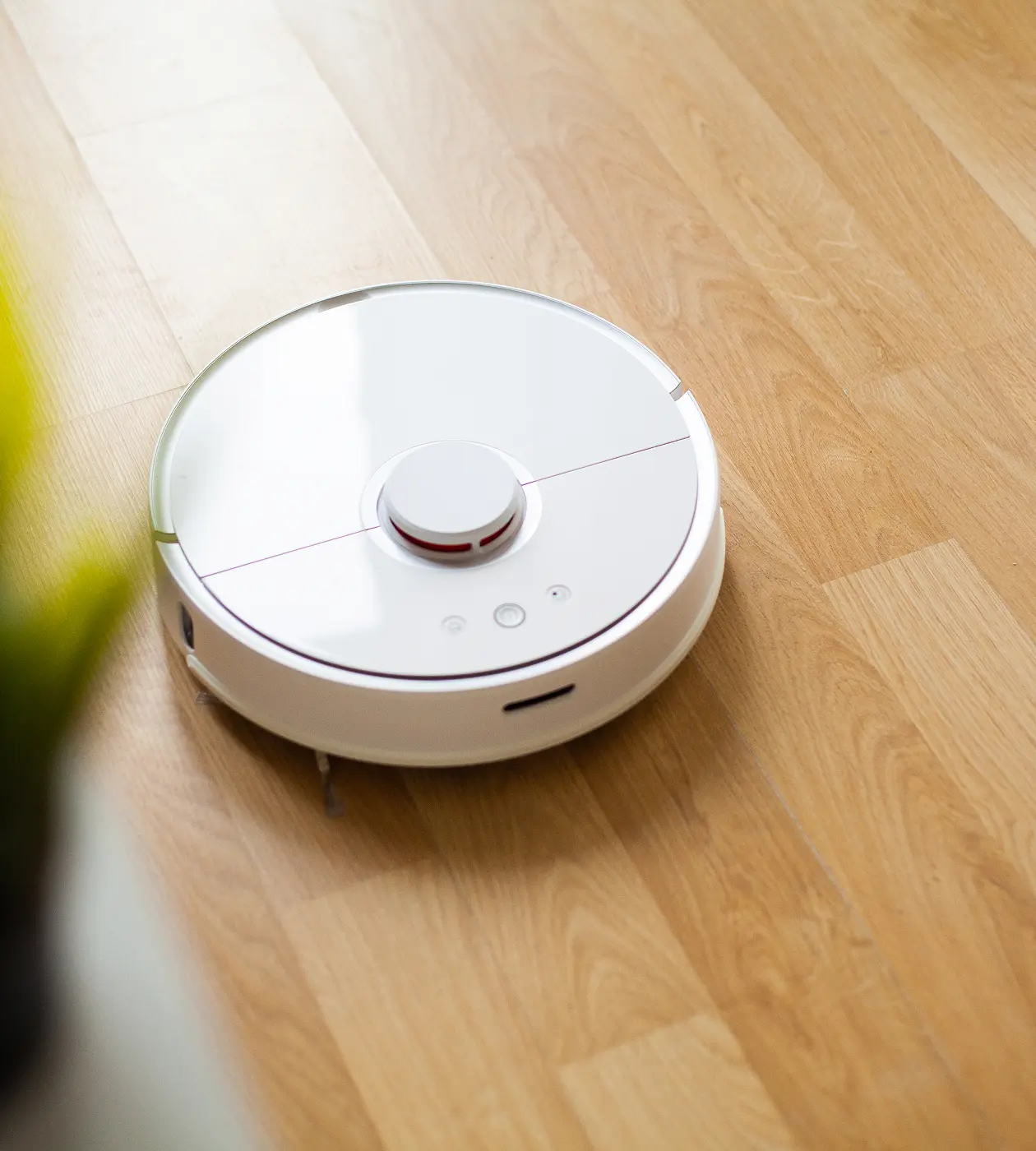 A white robotic vacuum cleaner resting on the floor, designed for automated cleaning tasks in home environments.